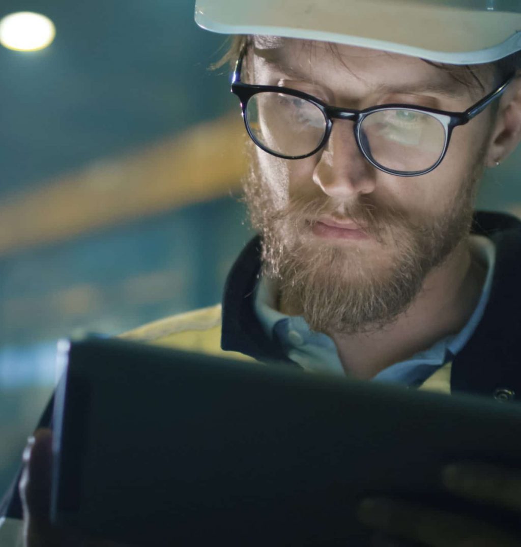 Engineer in glasses and white hard hat completing work on writing pad